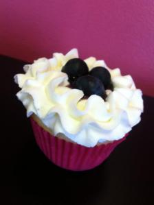 White cupcake with blueberry filling topped with vanilla buttercream and fresh blueberries.